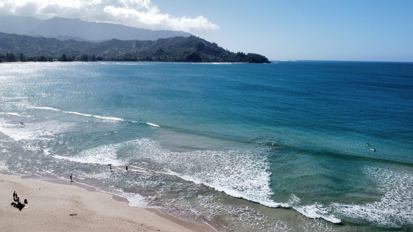 Hanalei Bay from the bluff above the beach, with surfers in the water and the mountain backdrop, 10 minutes from Princeville
