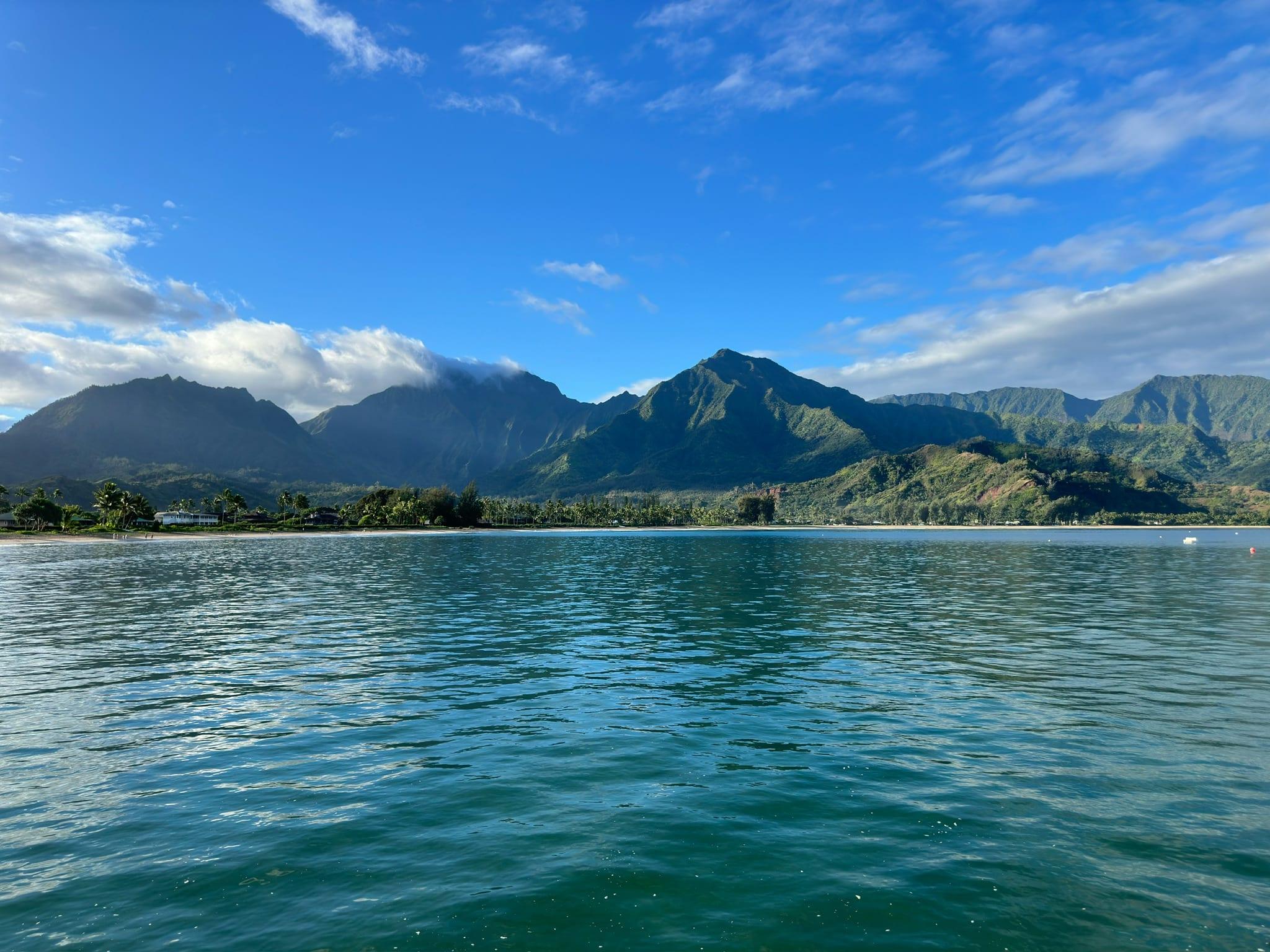 Wide water-level view of Hanalei Bay with the mountains behind, the easiest broad sand beach near Princeville