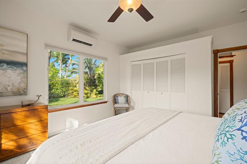 Bright guest bedroom with abstract art and ceiling fan at Emmalani Hale