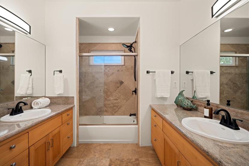 Guest bathroom with dual granite vanities and tub-shower combo at Hale
