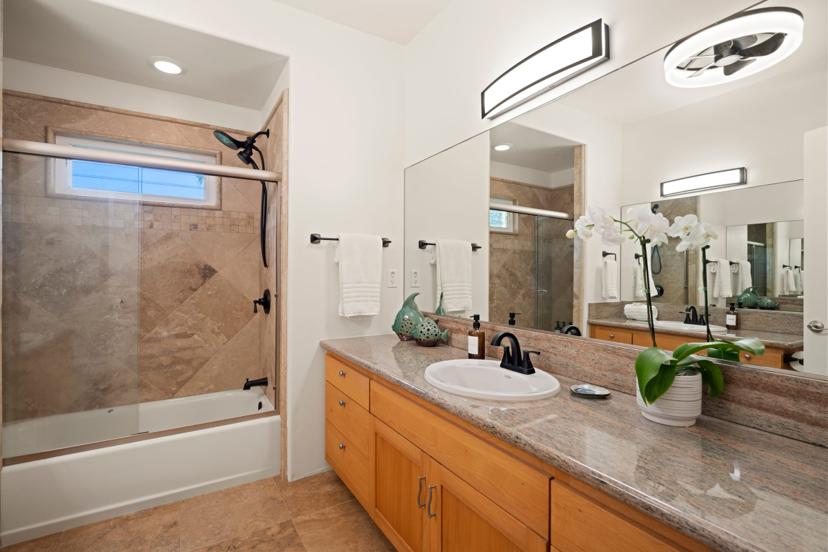 Guest bathroom with granite vanity and tub-shower at Emmalani Hale Kauai