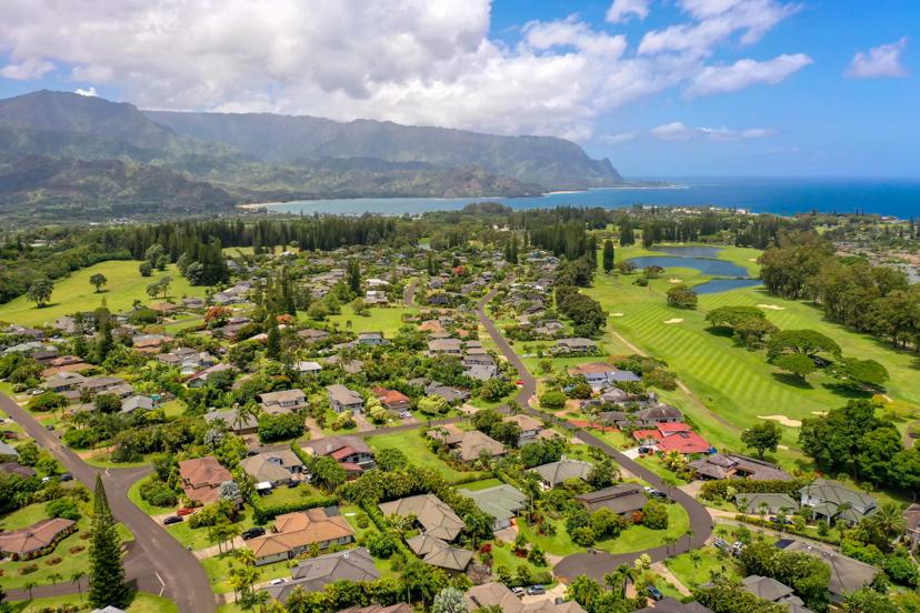 Aerial of Princeville neighborhood with North Shore mountains and ocean horizon