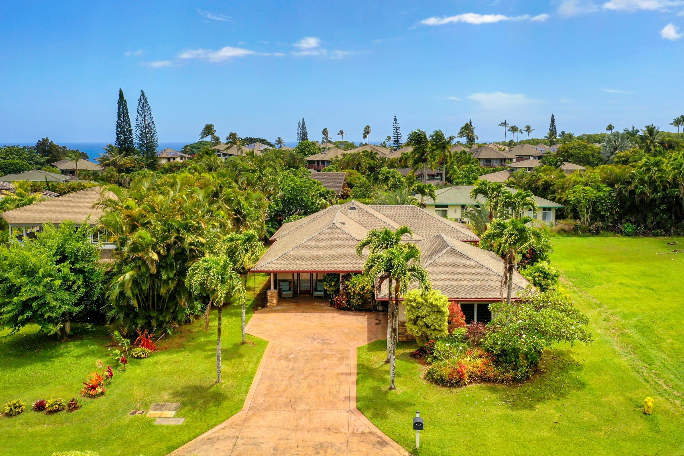 Drone aerial view of Emmalani Hale, a luxury Princeville Kauai vacation rental, with the North Shore ocean horizon in the distance