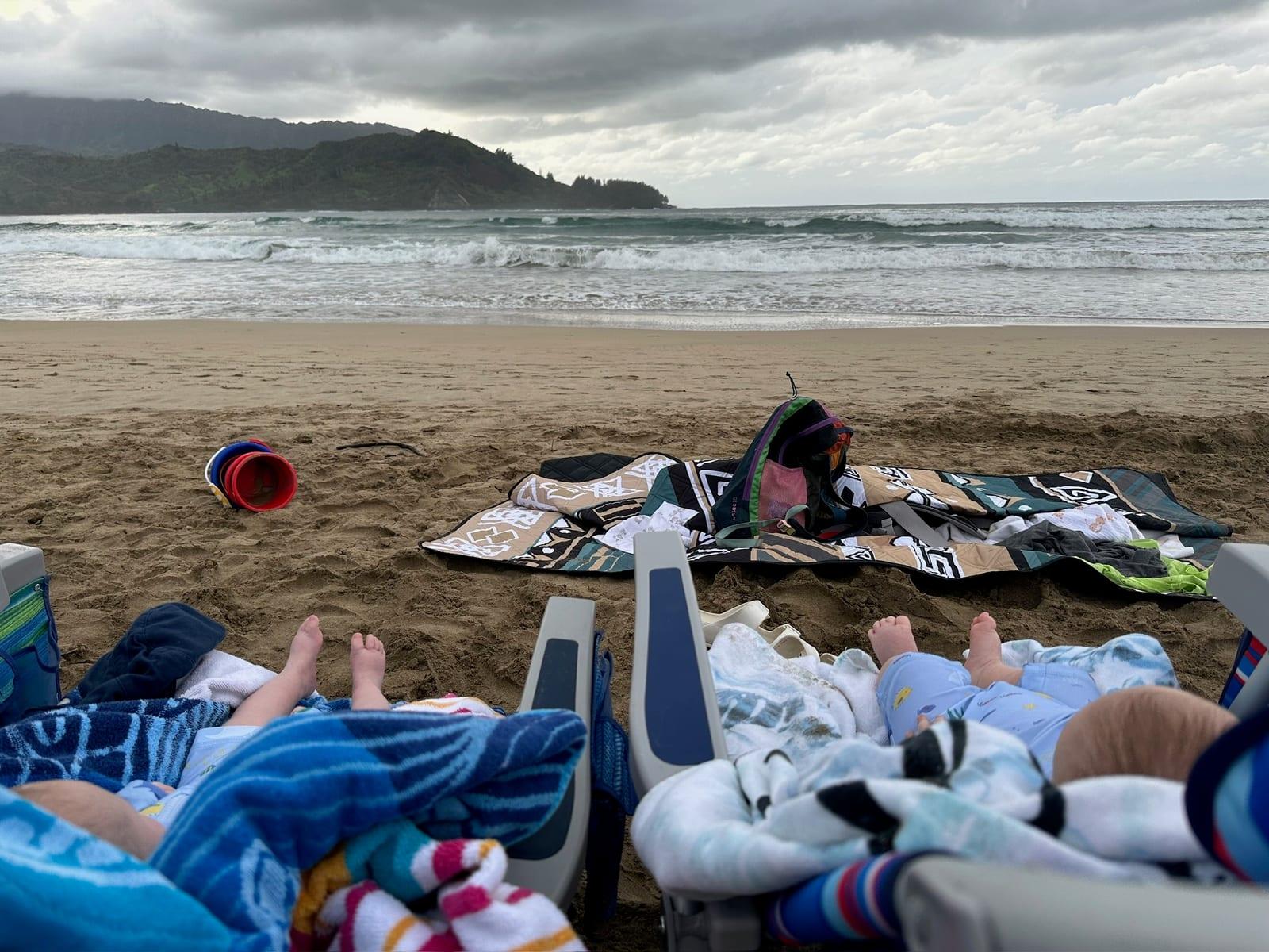 Kids in beach chairs at Hanalei Bay with towels and sand toys, the kind of easy North Shore beach day a Princeville family packing list should cover